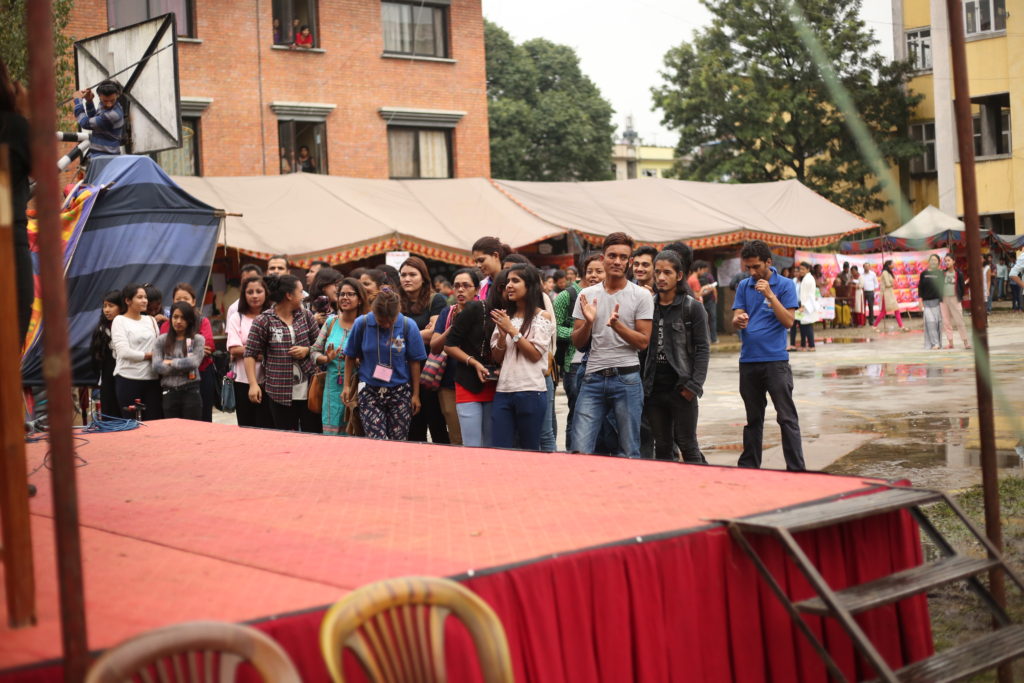 Some Audiences enjoying the performance while other visitors visiting the stalls for information.